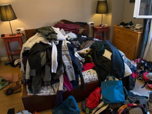 piles of clothes disorganized inside person's bedroom