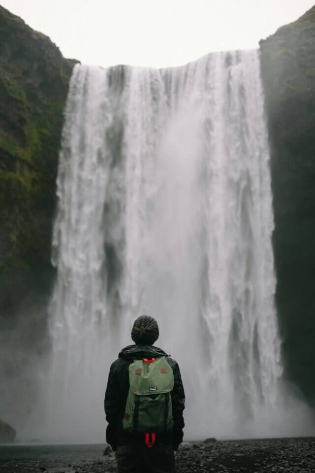 Man with patagonia backpack by waterfall