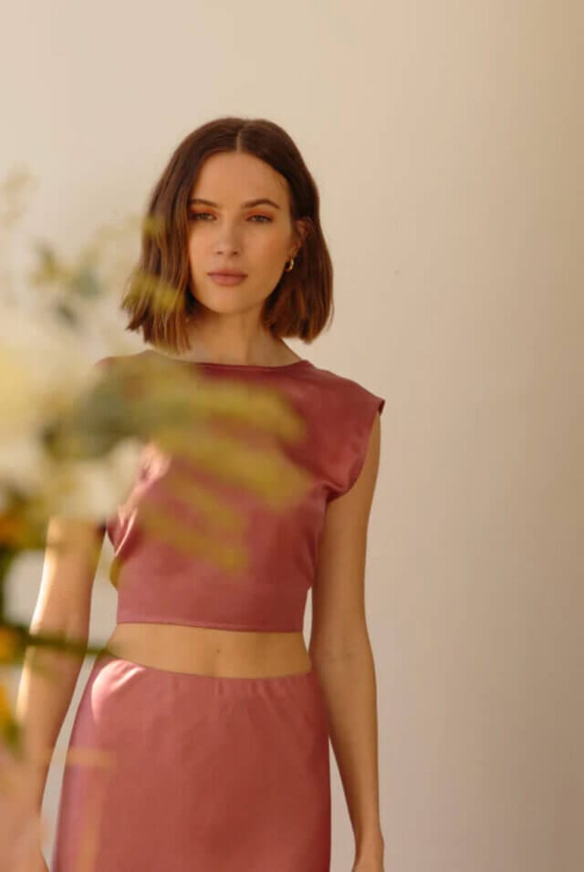 Woman wears a pink silk skirt and top co-ord with pink eyeshadow