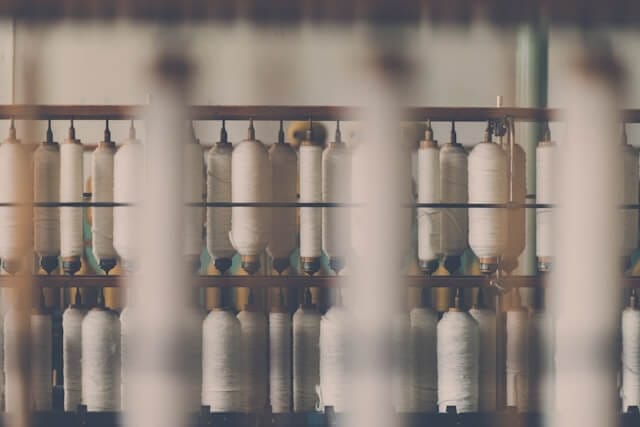 An image of threads in manufacturing facility. Image by Janko Ferlic from Unsplash