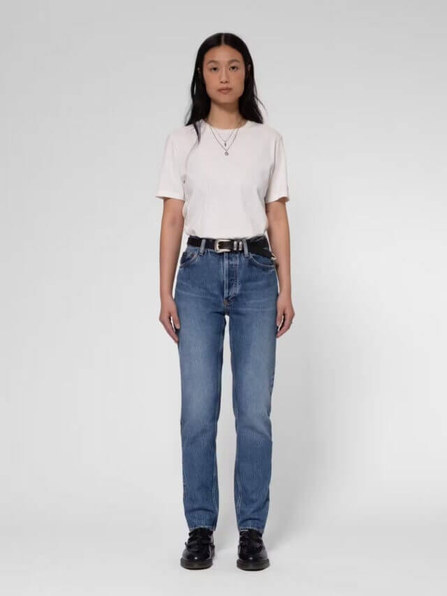 A woman with long dark hair wears a high-waist regular-fit jeans with a tapered leg made from organic cotton by Nudie.