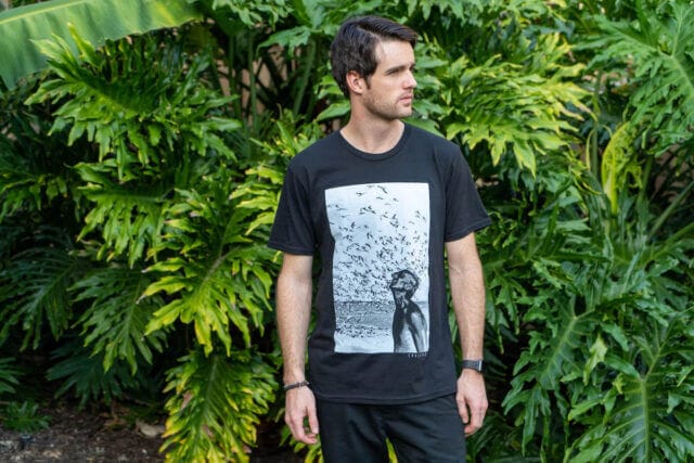 A man stands with the Jacques Cousteau Organic Cotton T-Shirt from Coalatree made with 100% Organic recycled cotton.