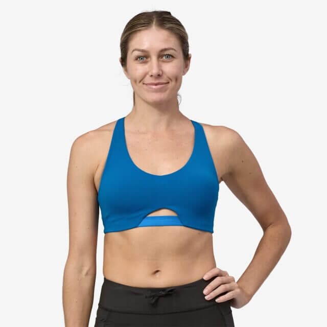 A woman stands on a white background with the Maipo Low-Impact Adjustable Bra from Patagonia.