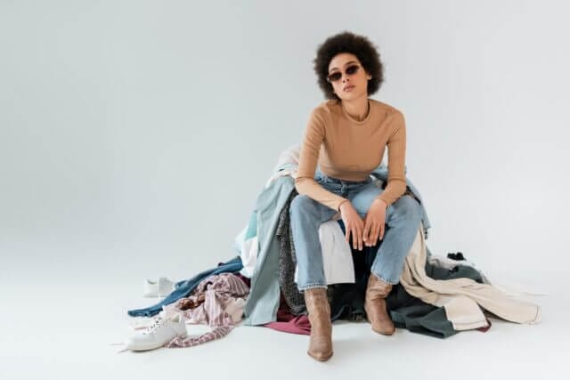 9 Sustainable Fashion Trends to Consider_woman sitting on clothes