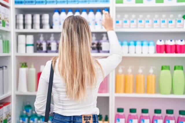 woman selecting a plastic shampoo bottle at the store