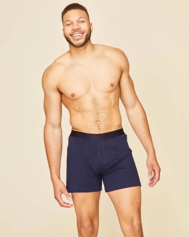 A tall man standing is wearing a navy boxer made with organic cotton by Subset. 