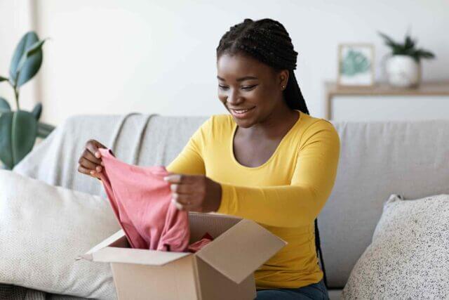 excited woman unboxes new clothes