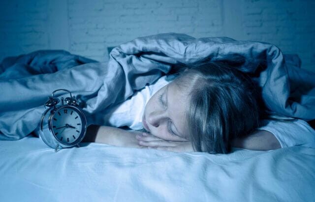 little girl sleeping in bed with alarm clock