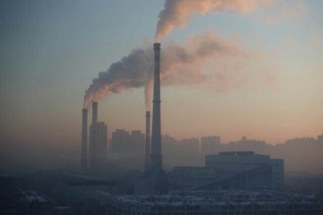 Towers from a plant emitting pollution through a smog 