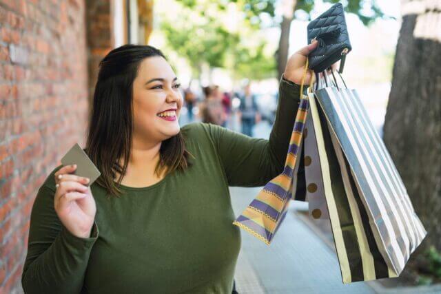 A happy woman smiling while showing her shopping bags.