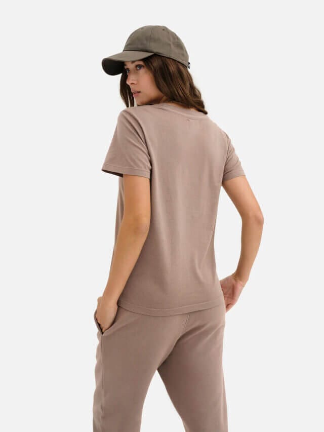 A female model is wearing a cap, t-shirt, and trousers from MATE the Label.