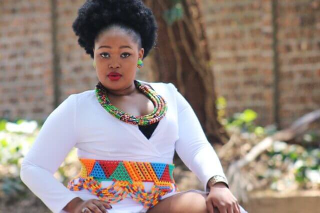 Plus-size model wearing a white dress with colourful accessories.