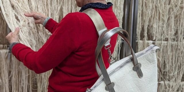 Person wearing the Pinatex bag made from pineapple leaf fibre whilst looking at the raw material.