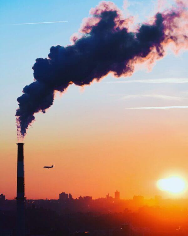 Chimney releasing toxic emissions into the sky at sunset.