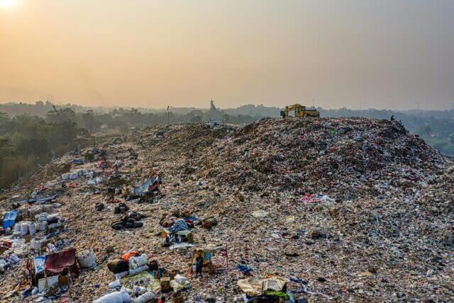 Mountains of discarded clothing and textile waste highlight the global scale of the fast fashion environmental impact.