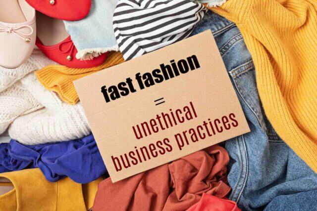 pile of clothes behind a sign that says fast fashion = unethical business practices