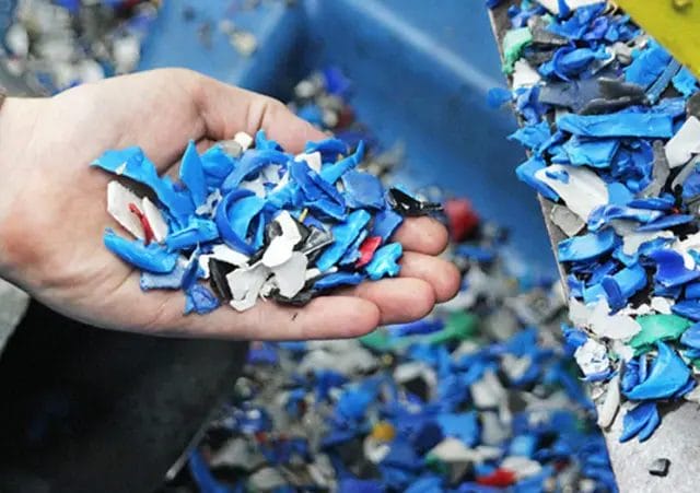 Hand holding plastic scraps ready for recycling