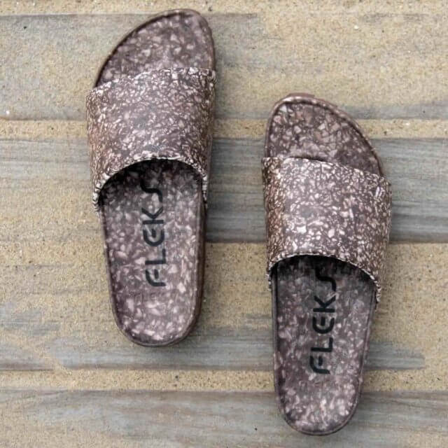 a pair of the FLEKS East Beach Slide outside on the beach in color coconut shell.
