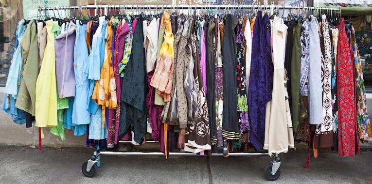 Rack of colorful second-hand clothes at a thrift market, representing eco-friendly fashion deals.